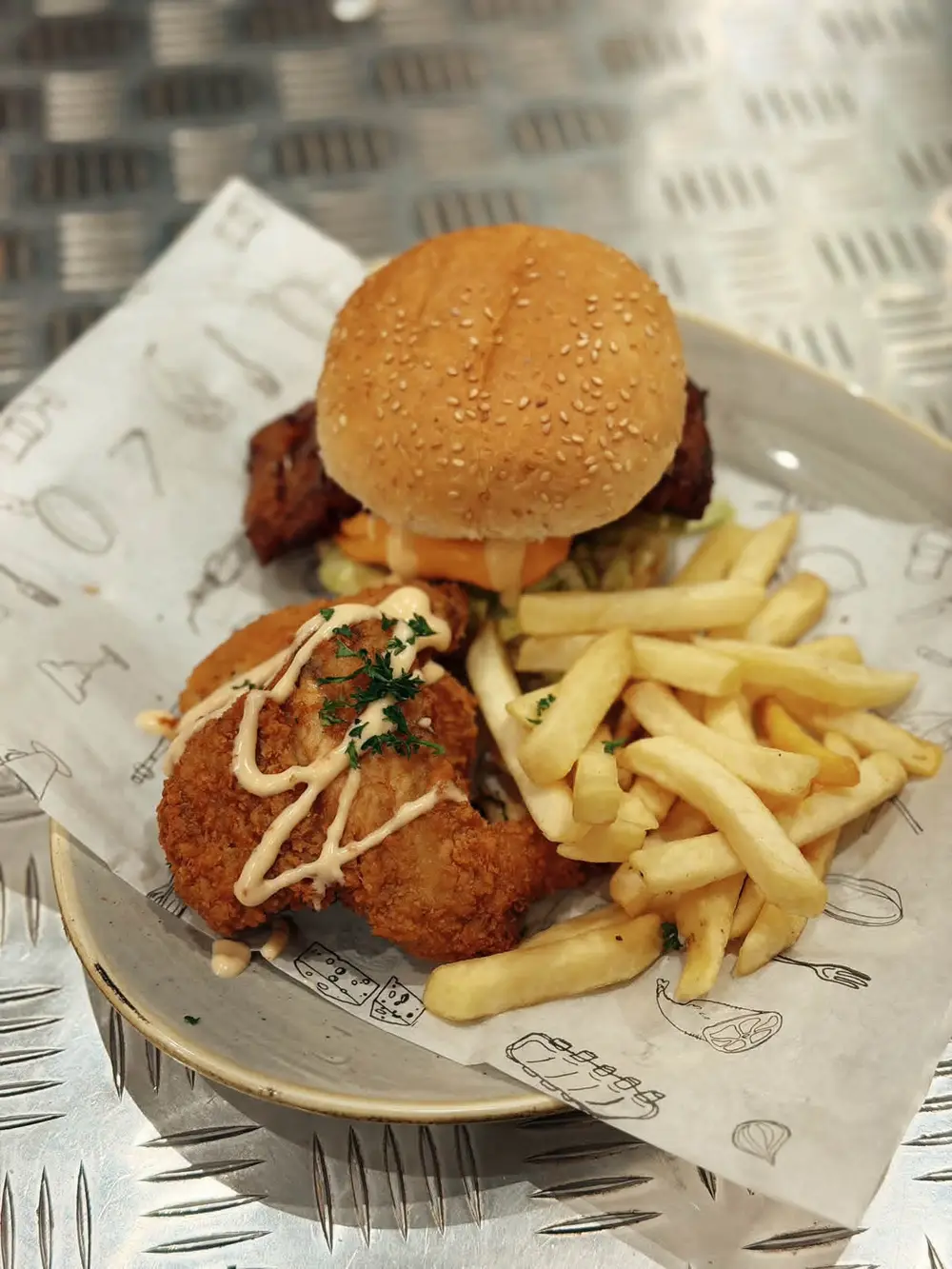 Chicken burger with crumbed chicken strips, drizzled sauce and chips