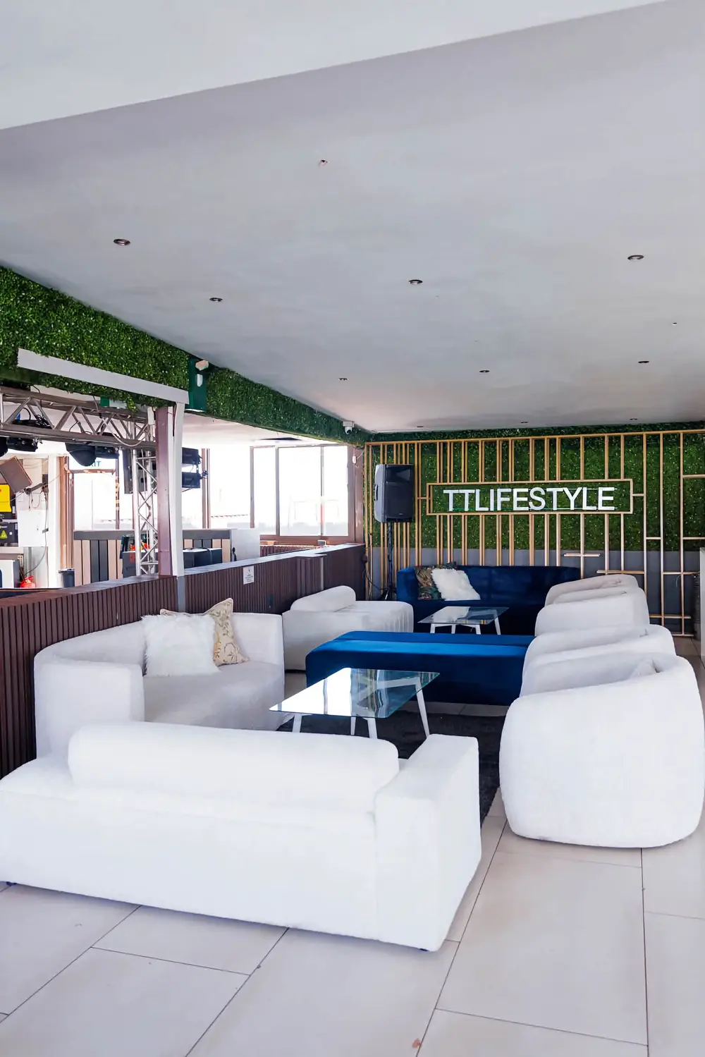 Indoor lounge with white boucle couches, blue velvet ottomans and a green wall with the TTLIFESTYLE sign